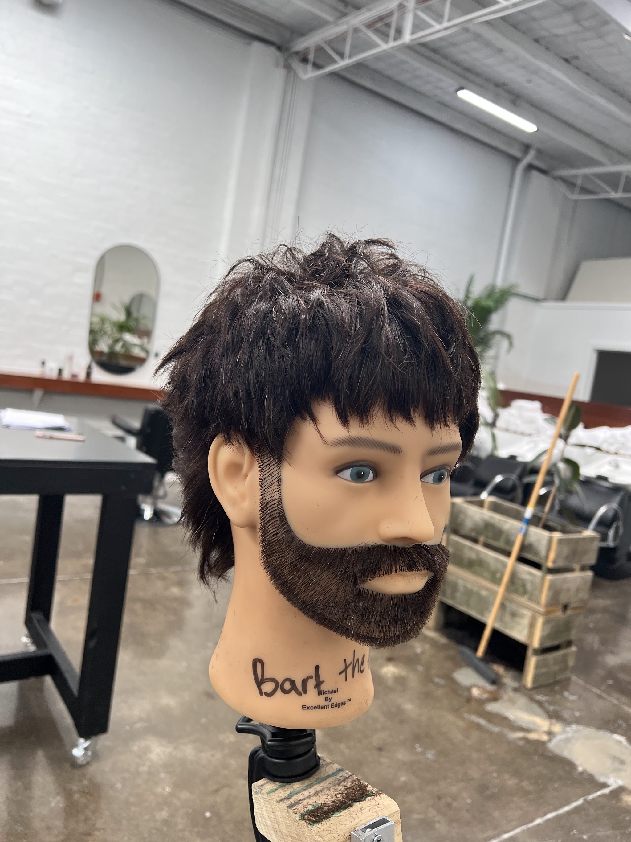A practice head on a bench clamp at a barbering education studio